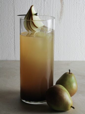 Cocktail in highball glass with pear and sliced pear garnish.