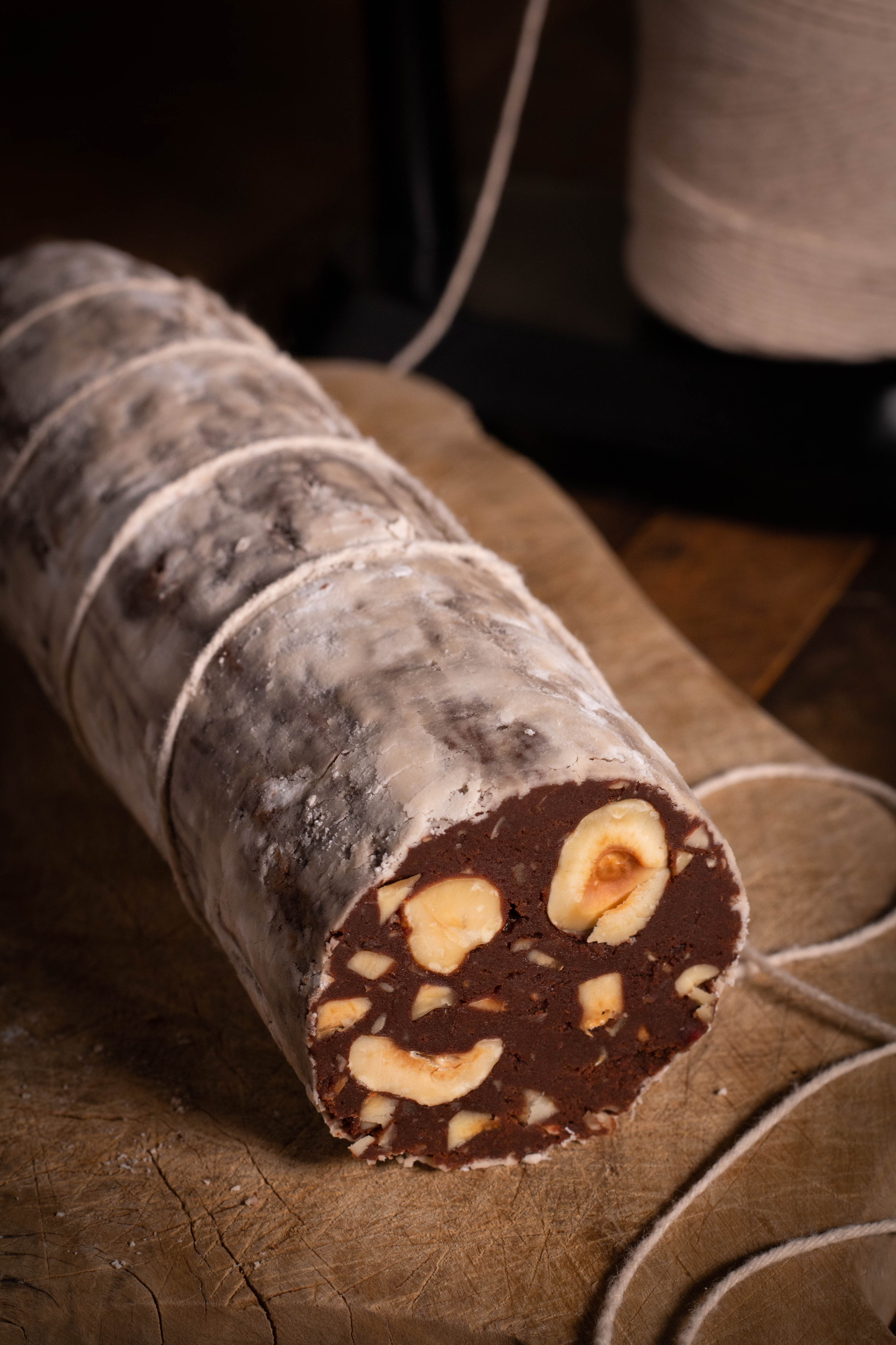 Chocolate Sausage with trussed with butcher's twine on an olive wood board.