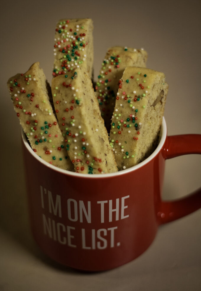 Red Mug that says, "I'm on the nice list." filled with biscotti with red and green sprinkles.