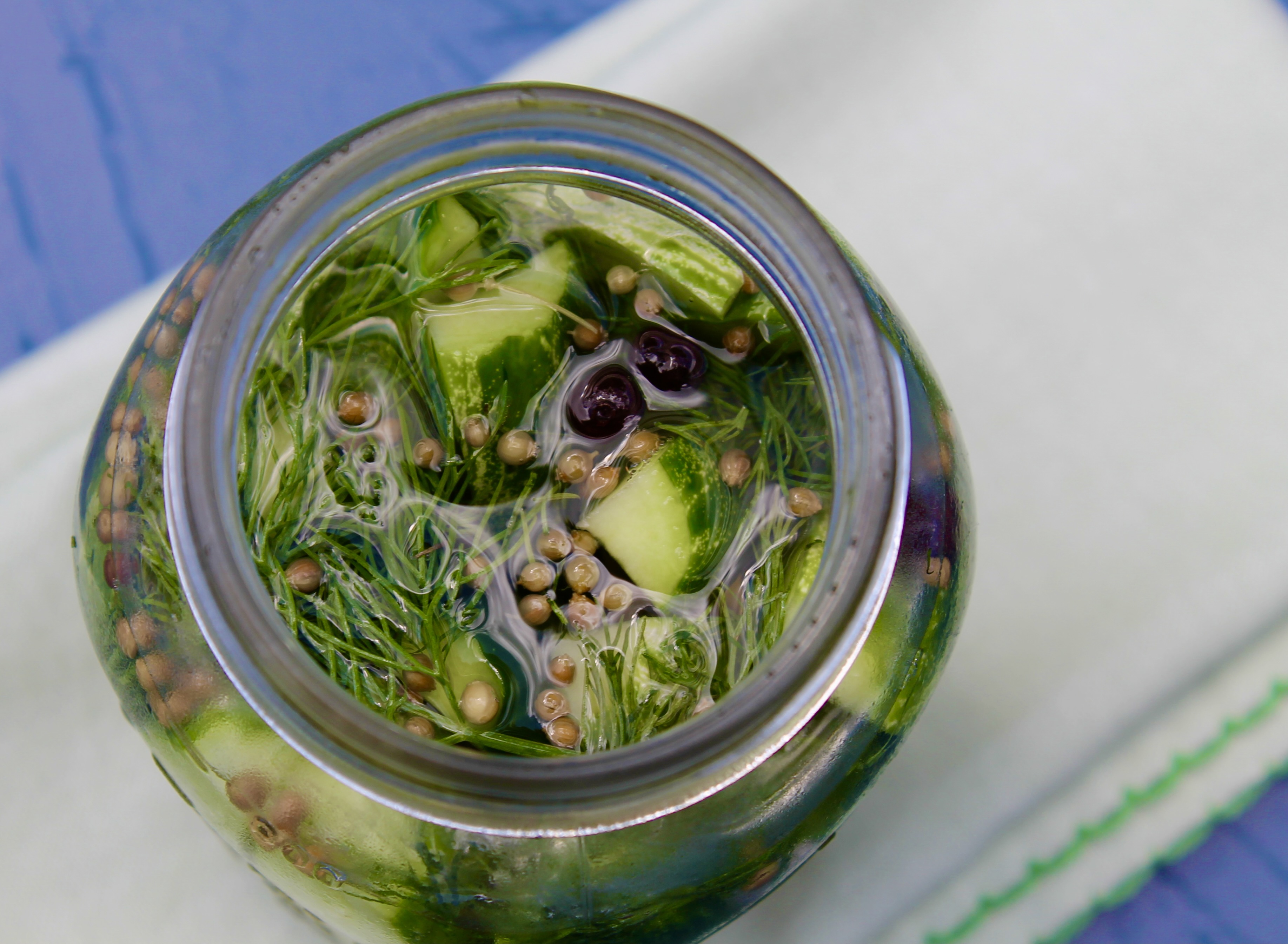 Mason jar with half sour pickles on a napkin.