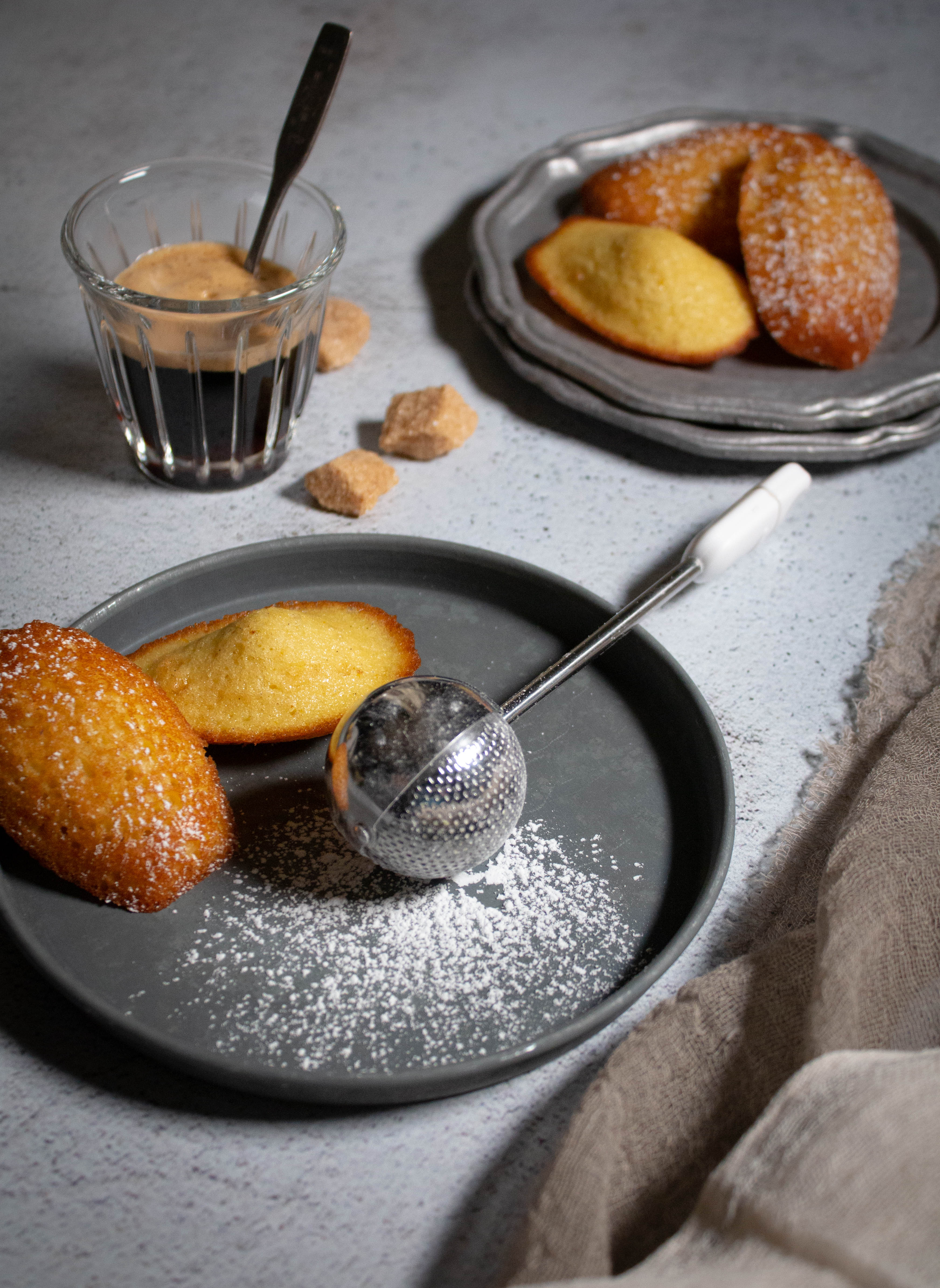 Madeleines on a plate with a sugar duster.